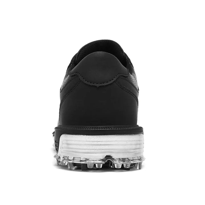 Rear view of a black athletic shoe with a reinforced toe cap, white midsole, and translucent cleats on the high-traction outsole, set against a plain white background.