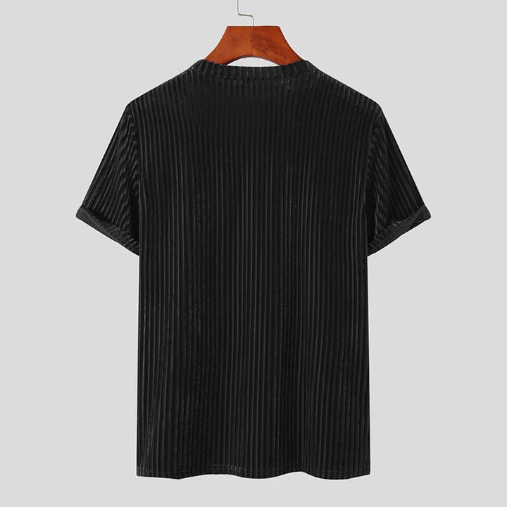 A black, short-sleeved, vertically striped velvet stripe corduroy tee with a classic fit is displayed on a wooden hanger, shown from the back against a plain light gray background.