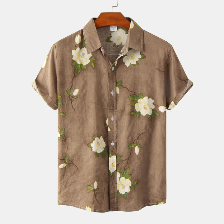 A brown short-sleeve floral shirt with white flowers and green leaves, perfect for summer style, displayed on a wooden hanger against a plain white background.