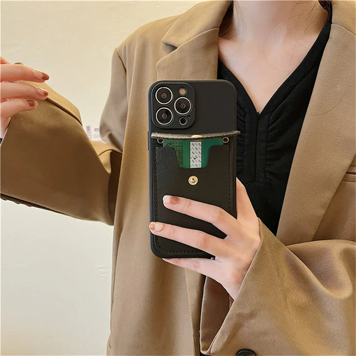 A person in a tan blazer and black top holds a smartphone with a phone case wallet featuring a secure cardholder pocket, displaying a green and white card partially inserted.
