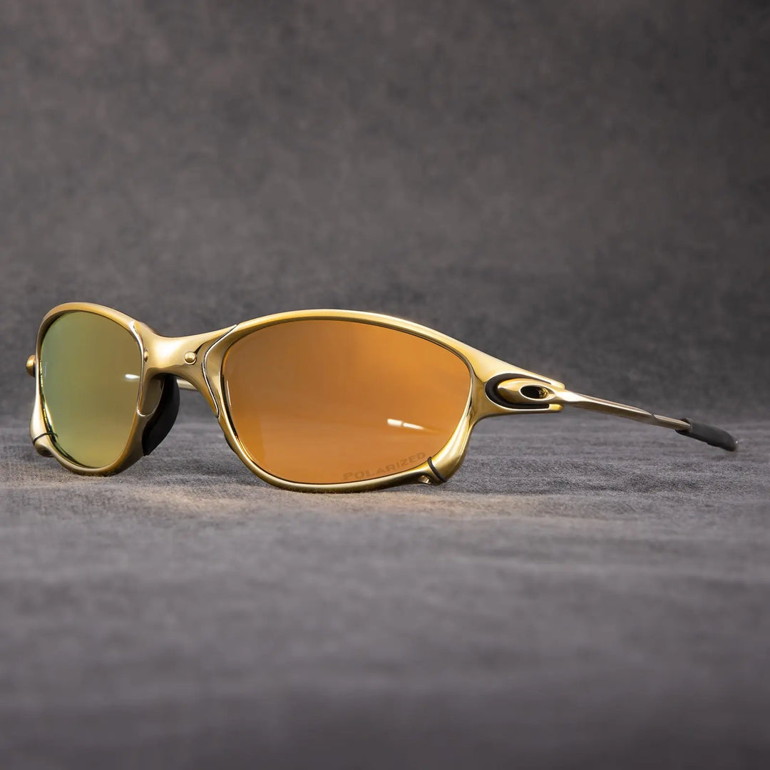 Gold-framed Oakley polarized sunglasses with orange-tinted, mirrored lenses offer exceptional UV protection. This premium outdoor eyewear is displayed on a gray textured surface with a dark gray background.