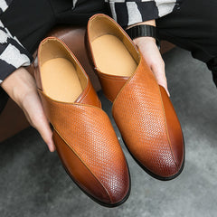 A person holds a pair of stylish genuine leather loafers in two shades of brown with a textured, crisscross pattern on the upper front and smooth leather accents. The low profile loafers feature a durable outsole, perfect for everyday elegance.