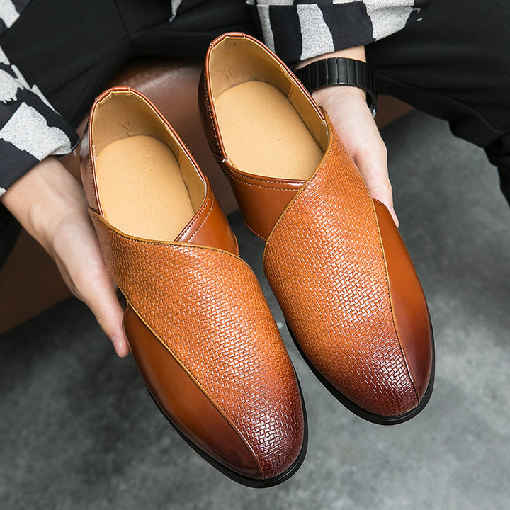 A person holds a pair of stylish genuine leather loafers in two shades of brown with a textured, crisscross pattern on the upper front and smooth leather accents. The low profile loafers feature a durable outsole, perfect for everyday elegance.
