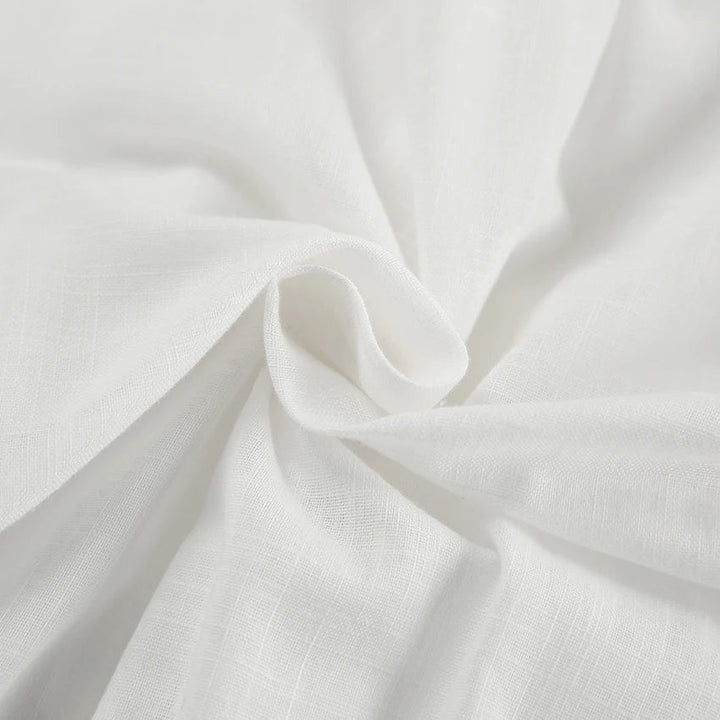 Close-up of soft, white fabric with a subtle texture, gently gathered and twisted in the center—perfect for a chic romper, adding natural folds and smooth flow ideal for a stylish summer outing.
