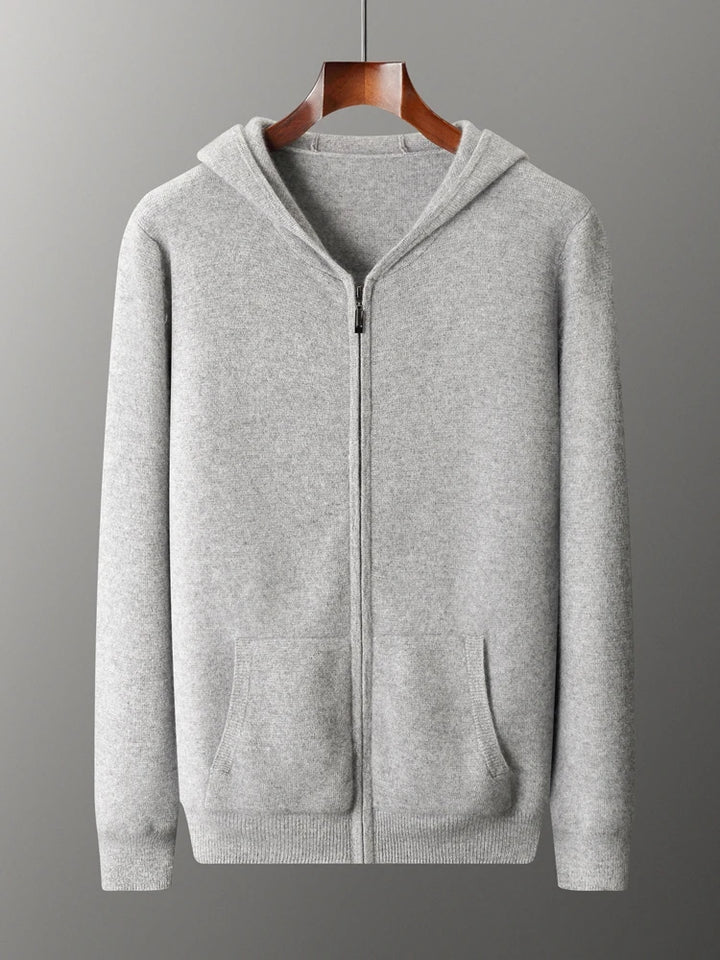 A light gray zip-up hoodie with a hood, front pockets, and ribbed cuffs and hem, displayed on a wooden hanger against a plain gray background—a cozy knit cardigan ideal for cool days.