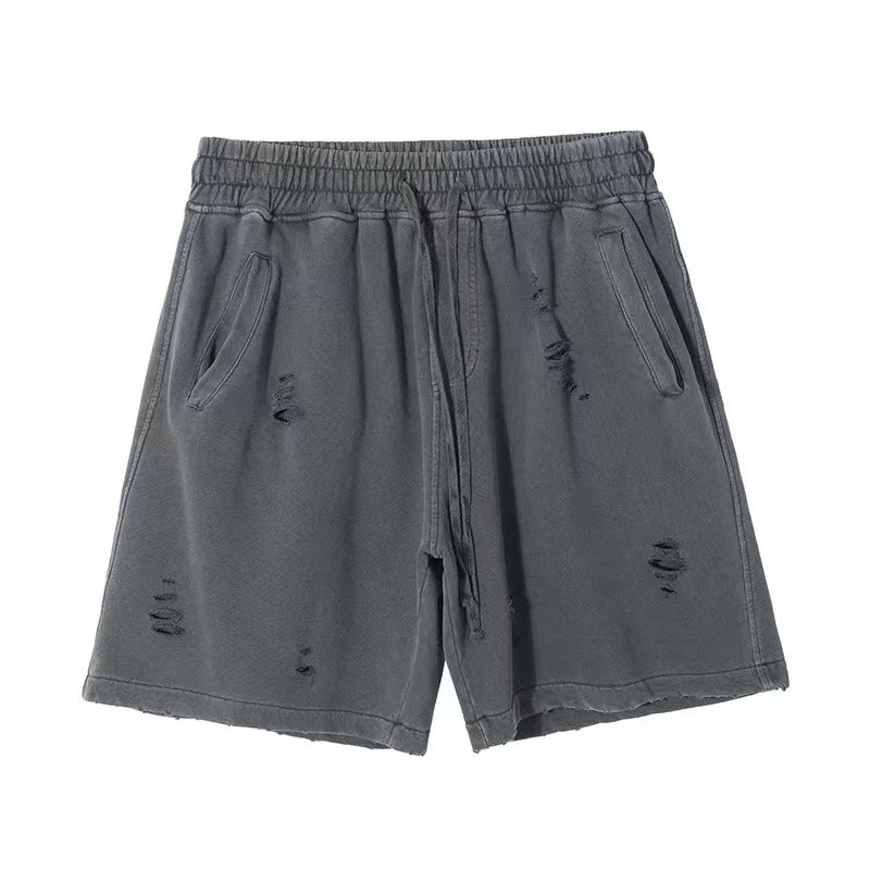 A pair of gray, vintage baggy shorts with an elastic waistband, drawstring, side pockets, and distressed details, laid flat on a white background.