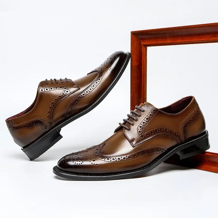 A pair of premium leather brogue dress shoes with decorative perforations, featuring a cushioned insole, displayed against a white background with a wooden frame element. One shoe stands upright while the other is angled upward.