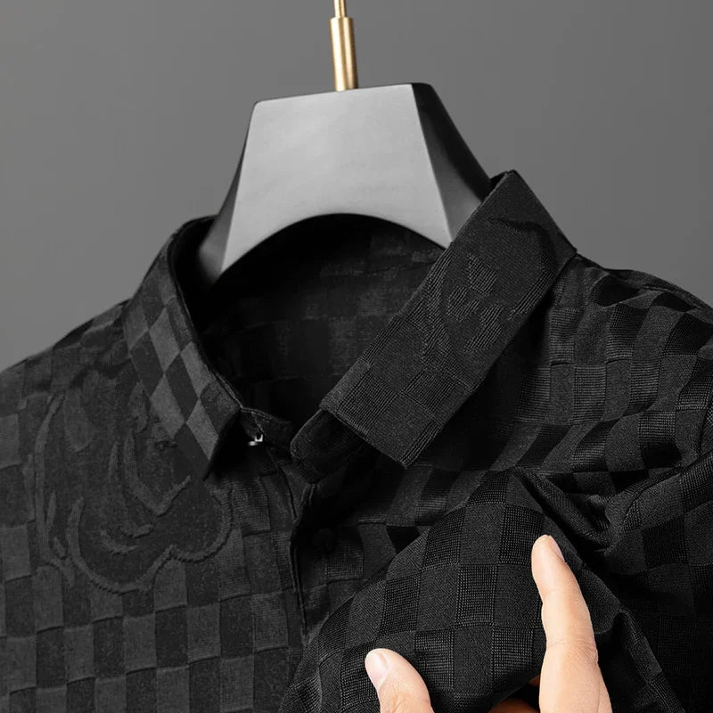 Close-up of a tailored fit black checkerboard pattern dress shirt on a hanger, with a hand holding one sleeve; the shirt features a subtle textured pattern and a pointed collar.
