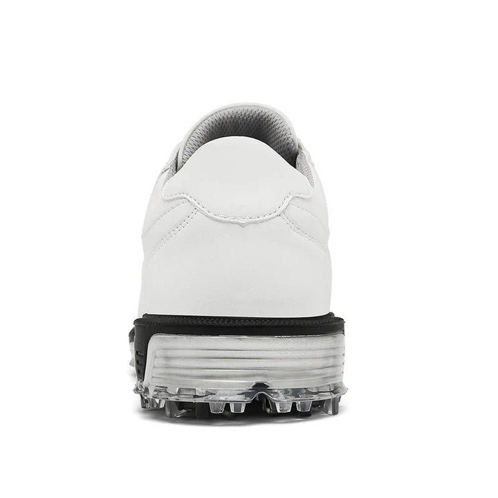 Rear view of a white athletic shoe with a high-traction outsole, thick black and gray sole, and transparent cleats, designed for sports or outdoor activities.