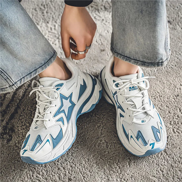A person wearing light blue jeans and white sneakers with a durable rubber outsole and star design stands on a beige textured carpet, with one hand adjusting their shoe.