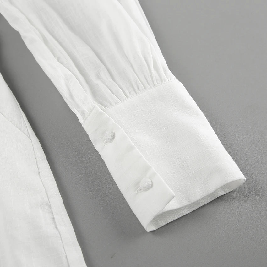 Close-up of a long-sleeve white shirt cuff with two white buttons, set against a plain gray background. The smooth, slightly textured fabric adds a touch of streetwear flair, perfect for elevating any summer outing look.