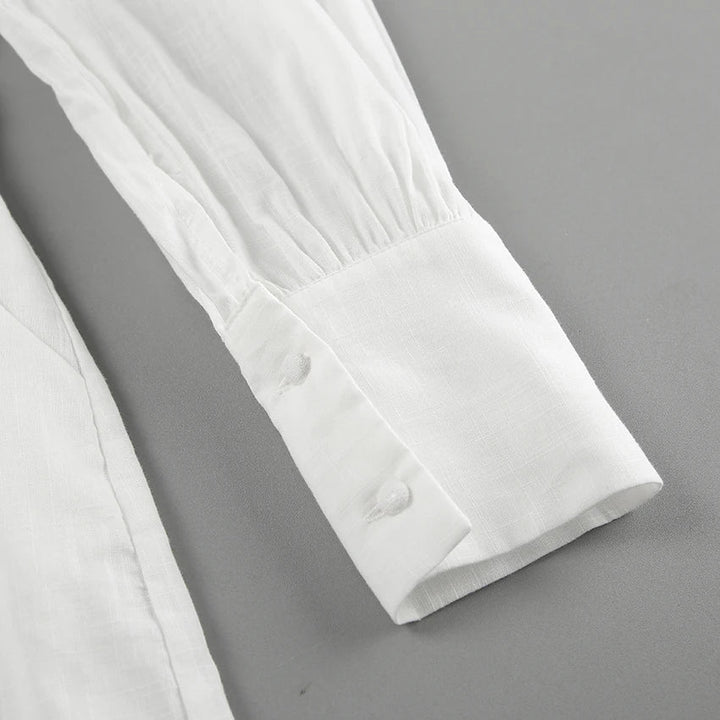 Close-up of a long-sleeve white shirt cuff with two white buttons, set against a plain gray background. The smooth, slightly textured fabric adds a touch of streetwear flair, perfect for elevating any summer outing look.