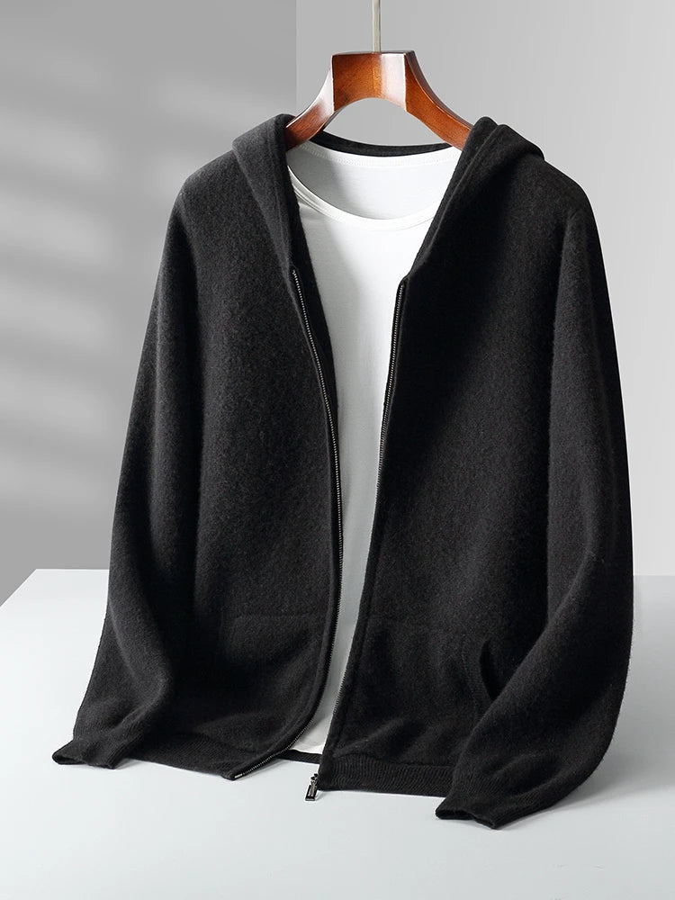 A black zip-up hoodie with a hood, displayed open over a plain white t-shirt on a wooden hanger against a light gray background, this look is perfect for layering with your favorite autumn winter cardigan.