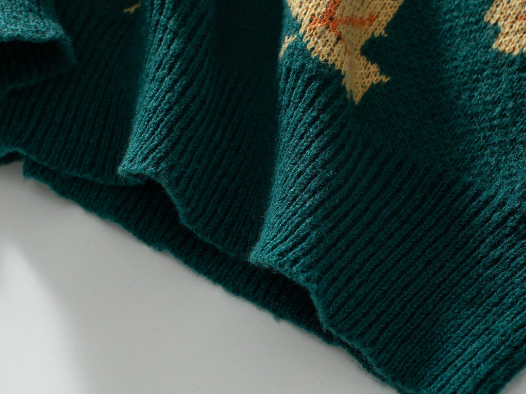 Close-up of the ribbed hem of a dark green comfortable sweater with a yellow pattern above the edge, crafted from soft knit material and lying flat on a light surface.
