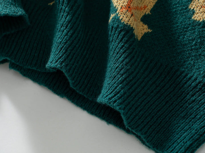 Close-up of the ribbed hem of a dark green comfortable sweater with a yellow pattern above the edge, crafted from soft knit material and lying flat on a light surface.