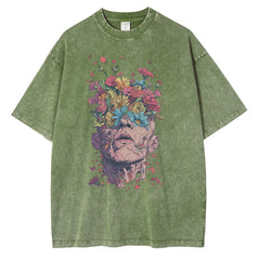 Olive green t-shirt in premium cotton with an oversized fit, featuring a striking graphic design of a human head blooming with colorful flowers and petals, blending surreal and botanical elements.