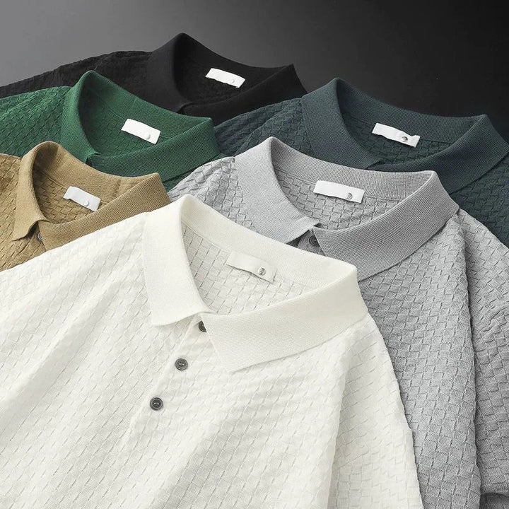 Six waffle jacquard polo shirts in white, beige, green, black, gray, and dark green are arranged in a fan-like pattern. Each features a collar and buttons, with the textured designs neatly overlapping on a flat surface.