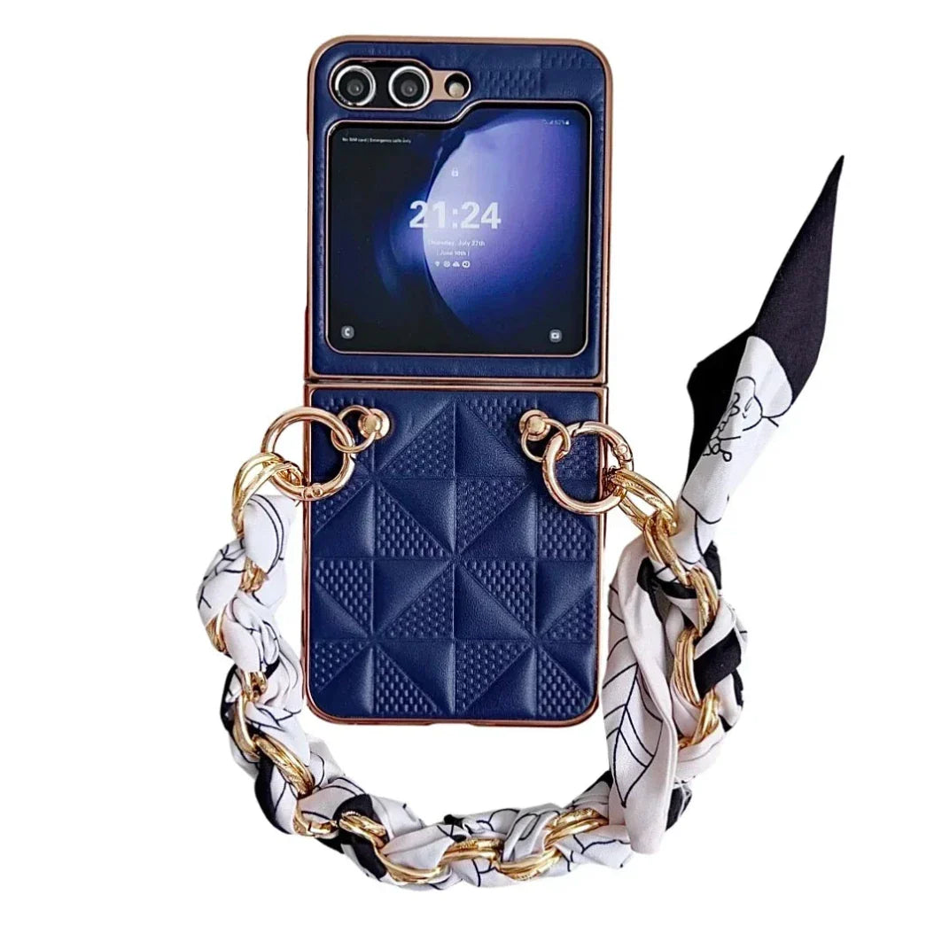 A Samsung Galaxy Z Flip in a premium leather case with shockproof protection, featuring a gold and black chain-link strap and patterned black and white fabric scarf. The foldable phone’s screen displays the time 21:24.