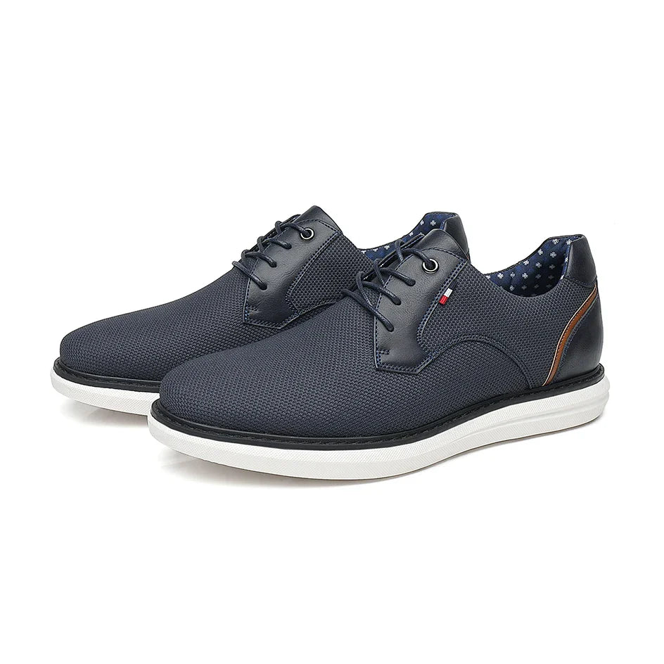 A pair of dark blue lace-up casual shoes with white soles, textured uppers, and a small brown accent on the heel. The inner lining is blue with white polka dots, blending traditional detailing with modern style.