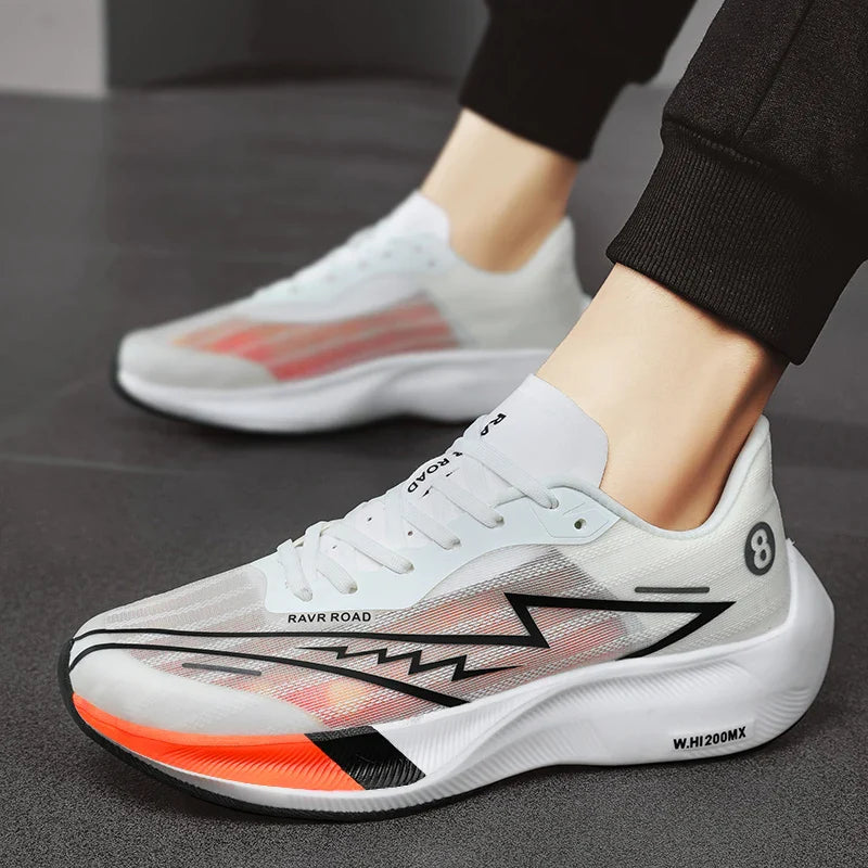 A person wearing white and gray athletic sneakers with black and orange accents, a zigzag design on the side, and the text RAVR ROAD and W.H 200MX on the sole featuring a shock-absorbing sole, stands on a dark surface.