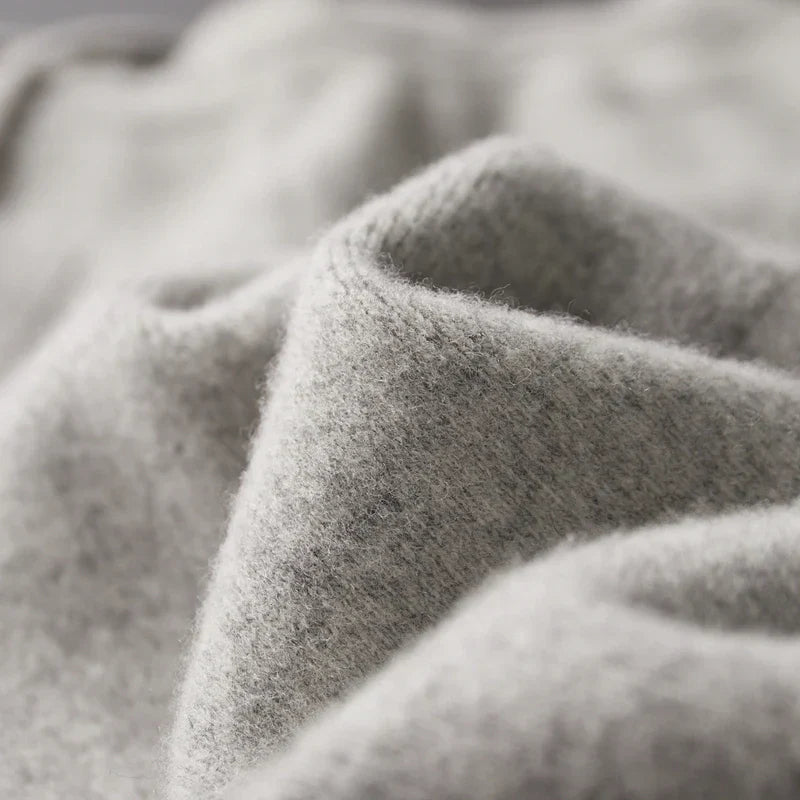 Close-up of a soft, light gray fabric with a fuzzy texture and gentle folds, crafted from a cashmere wool blend, suggesting winter warm comfort.