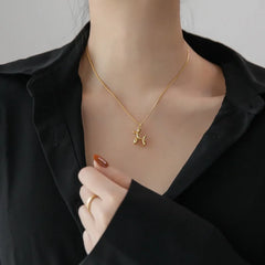 A person wearing a black shirt displays a playful balloon dog necklace with an adjustable chain. Their hand, with painted nails and a gold ring, is visible near the collar.