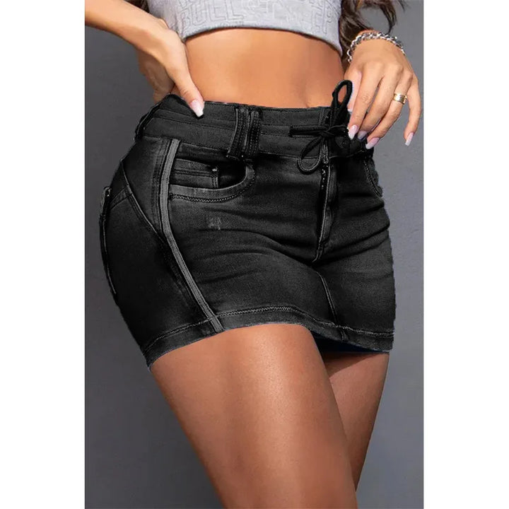A woman wears a high waist, black denim skirt with zipper details and a drawstring waist, crafted from premium cotton, paired with a cropped, light-colored top.