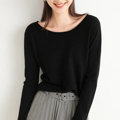 A woman wearing a black cashmere blend long-sleeve top and high-waisted black-and-white checkered pants with a relaxed fit stands against a white background, smiling with her hair down. Her face is partially visible.