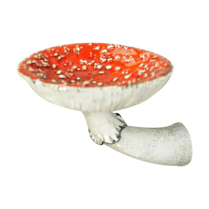 A ceramic sculpture featuring a naturalistic design, this red-and-white spotted mushroom cap with a white stem makes for unique home decor, set against a plain white background.