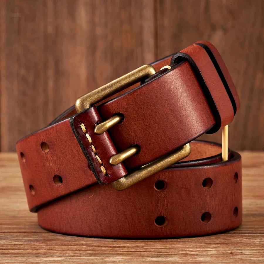 A durable cowhide leather belt with multiple holes and a brass buckle, coiled neatly on a wooden surface with a wooden background.