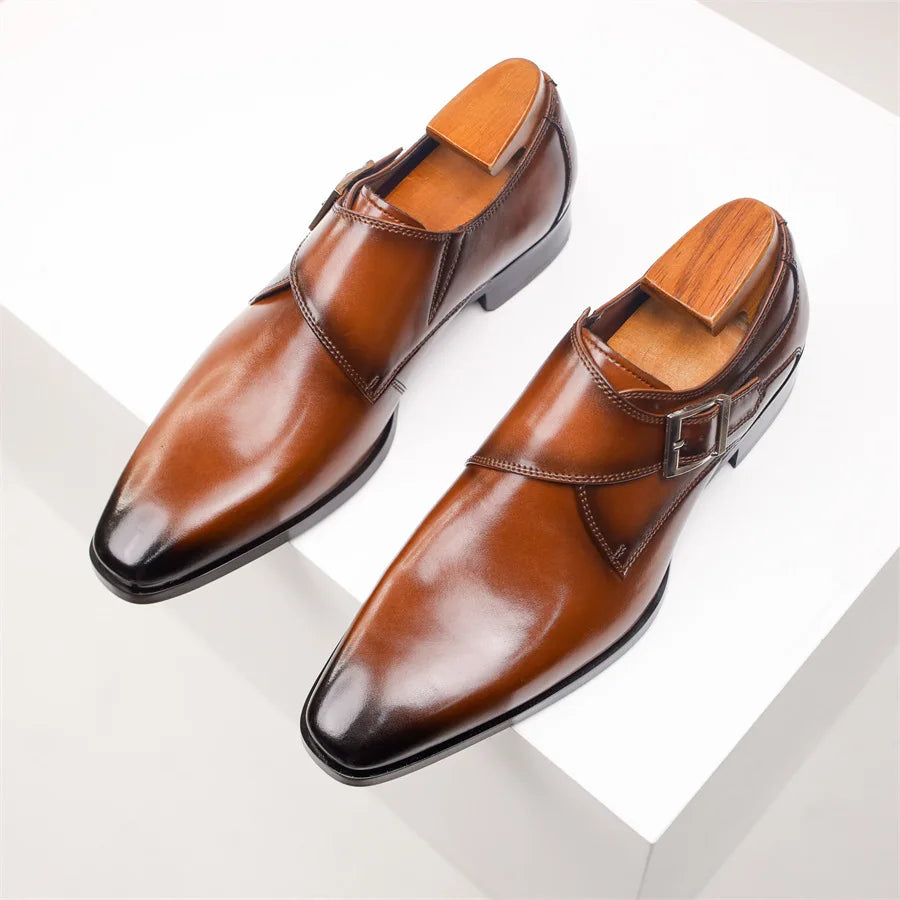 A pair of polished Italian leather monk strap shoes with wooden shoe trees inside, displayed on a white surface.