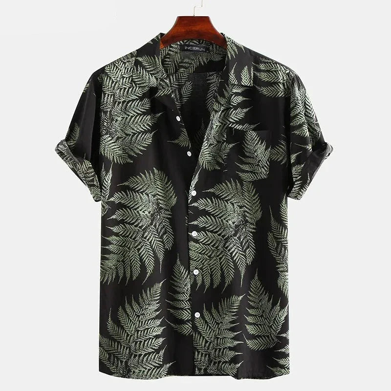 A classic design, short-sleeve cotton shirt with a black background and a green fern leaf pattern. Perfect for a casual brunch, its displayed on a wooden hanger against a plain white background.