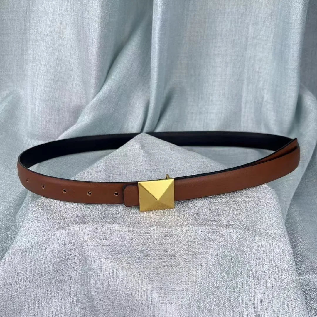 A brown leather belt with a large, square gold buckle and adjustable length is displayed on a light gray textured fabric background.