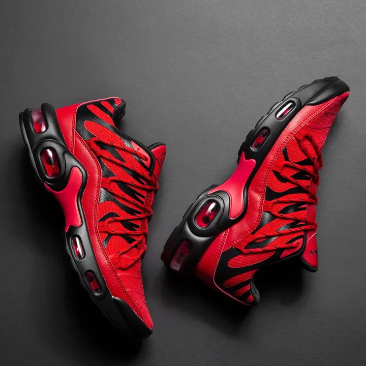 A pair of stylish red and black athletic sneakers with a breathable mesh upper, bold patterns, and black soles, displayed on a dark background.