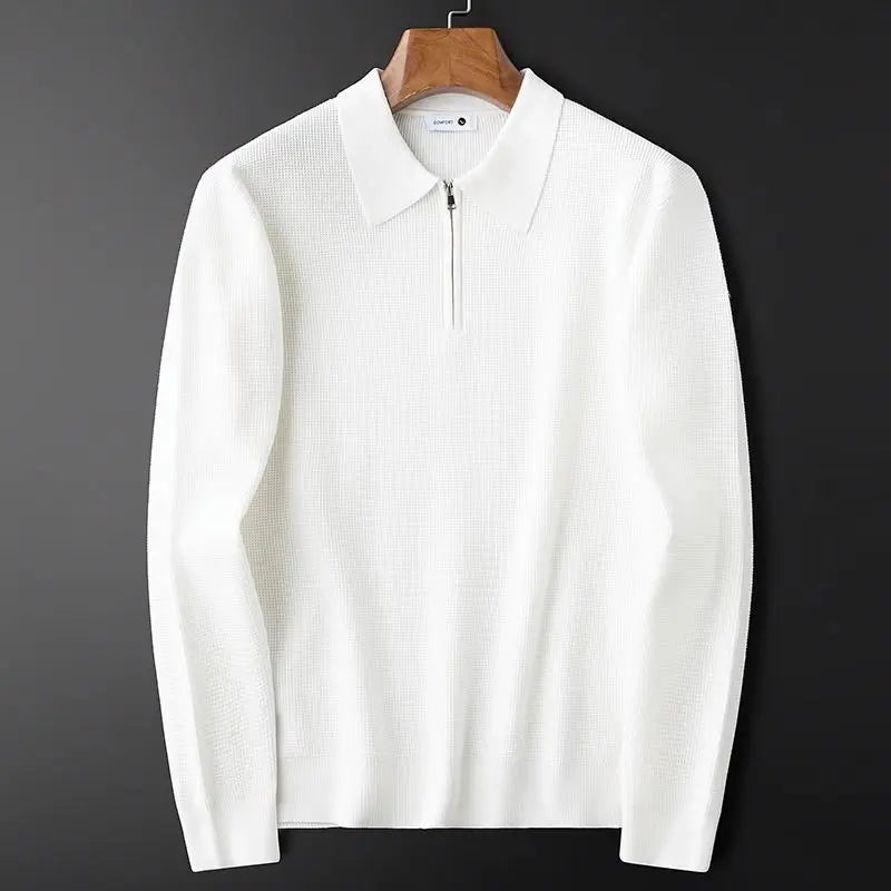 A white long sleeve polo knit sweater with a collar and short front zipper, crafted from stretchy fabric, displayed on a wooden hanger against a black background.