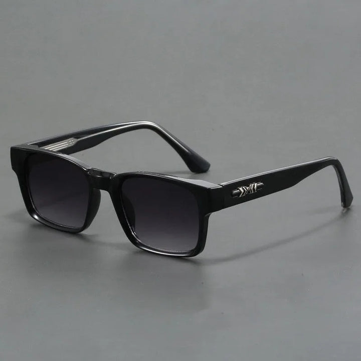 Black rectangular sunglasses with thick, durable frames and dark lenses, featuring a small silver decorative detail on the arms. Boasting UV400 protection and modern design, theyre displayed on a plain grey background.