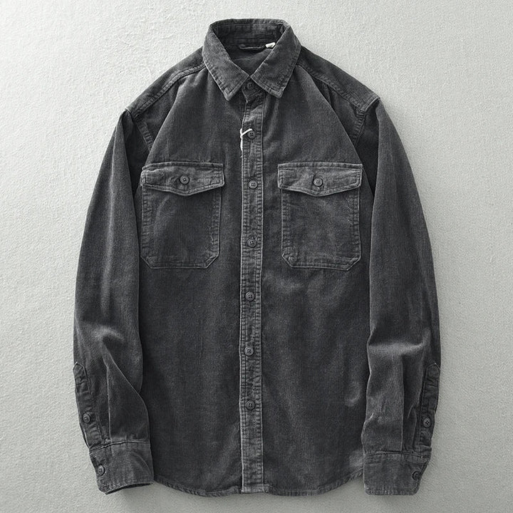 A long-sleeve, button-up shirt crafted from heavyweight cotton with classic corduroy detailing, featuring two buttoned chest pockets, displayed flat on a light gray surface.