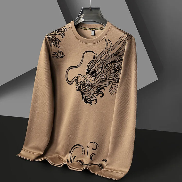 A light brown mens crewneck long-sleeve shirt featuring a large, detailed black dragon illustration on the front, displayed on a hanger against a geometric gray and black background.