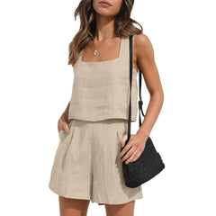 A woman in a sleeveless beige linen set with shorts and a square neckline top, holding a black woven shoulder bag, poses with one hand in her pocket against a white background for a chic contemporary style.