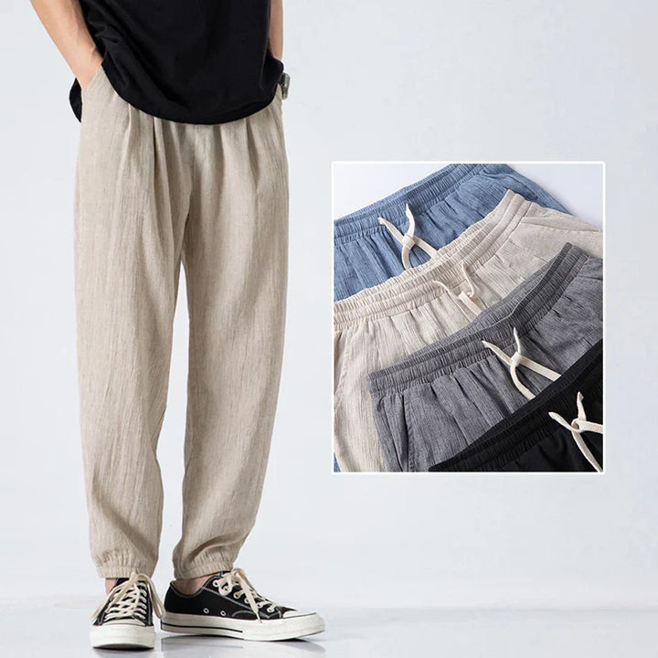 A person wearing comfortable, light beige drawstring linen pants and black sneakers stands next to an inset showing the same modern design in blue, gray, black, and beige, all with elastic cuffs and drawstrings.