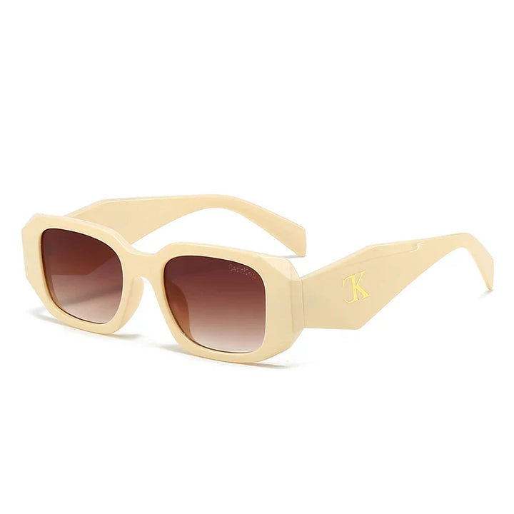 Beige oversized acetate sunglasses with thick frames, brown gradient lenses offering UV400 protection, reinforced hinges, and a gold K logo on the arms, shown at an angle against a white background.
