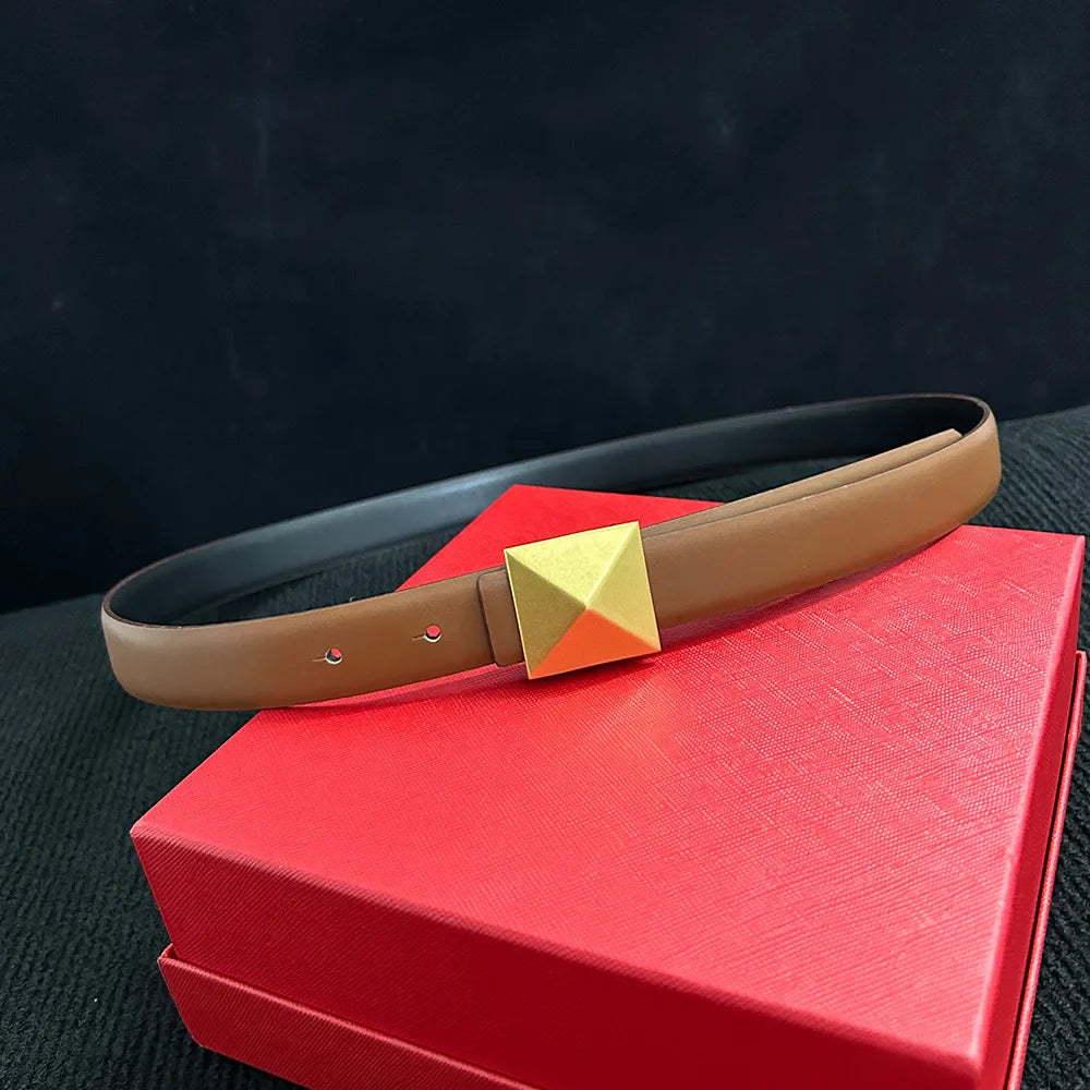 A brown leather belt with a large, square gold buckle is displayed on a closed red textured box against a dark background.