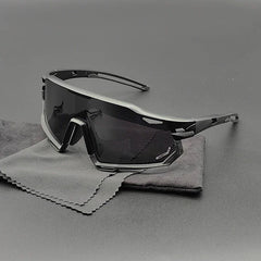 A pair of modern, angular black Olympus Sunglasses with polarized lenses and dark shades rests on two soft cleaning cloths atop a gray surface.