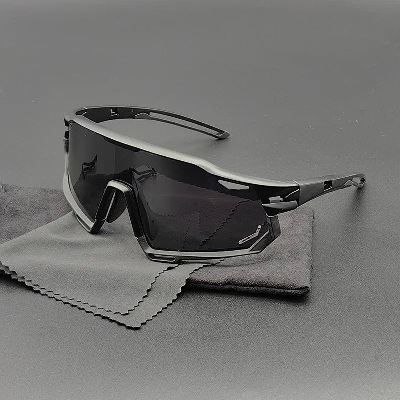 Angular, black wraparound Olympus Sunglasses with dark polarized lenses rest on a gray cleaning cloth and black surface, creating a sleek and modern aesthetic with superior UV protection.