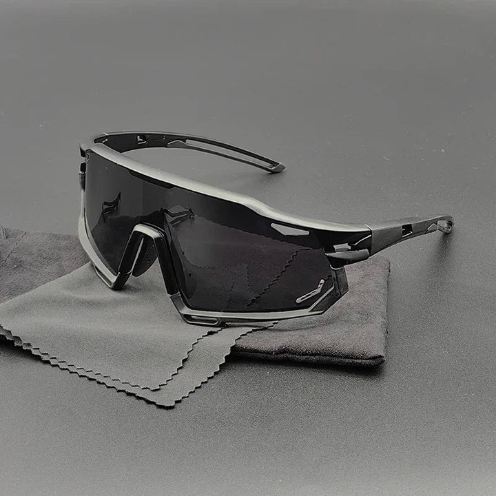 Angular, black wraparound Olympus Sunglasses with dark polarized lenses rest on a gray cleaning cloth and black surface, creating a sleek and modern aesthetic with superior UV protection.