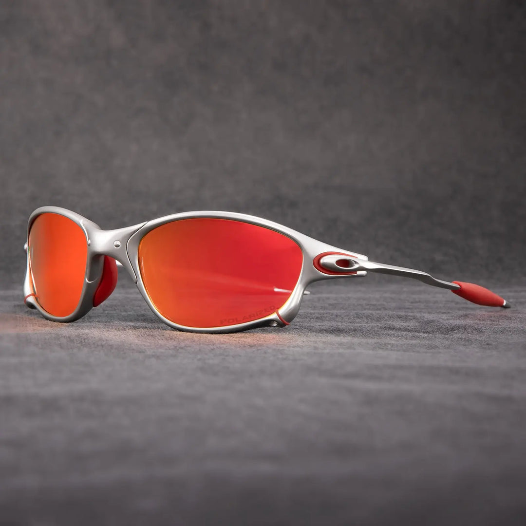 Silver-framed polarized sunglasses with red-orange mirrored lenses and red accents on the nose pads and temple tips, displayed on a gray textured surface with a plain background—perfect outdoor eyewear offering reliable UV protection.