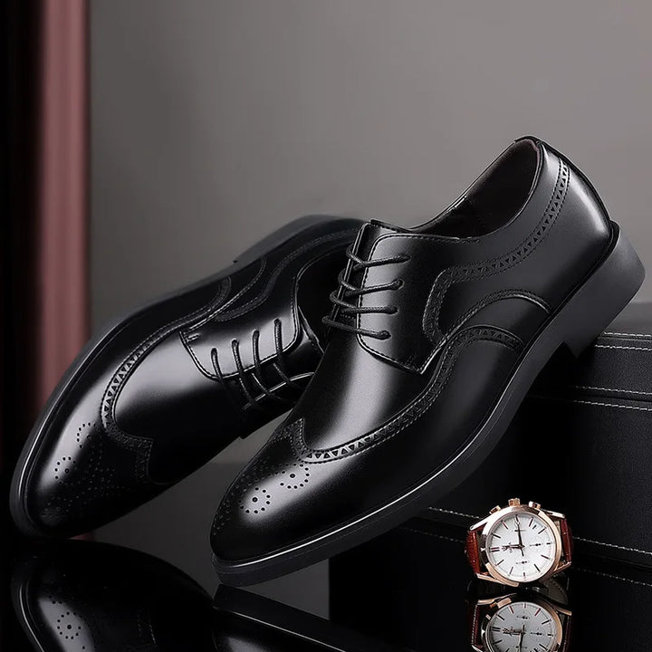 A pair of premium leather shoes with brogue detailing is displayed on a black surface next to a brown-banded wristwatch with a white face.
