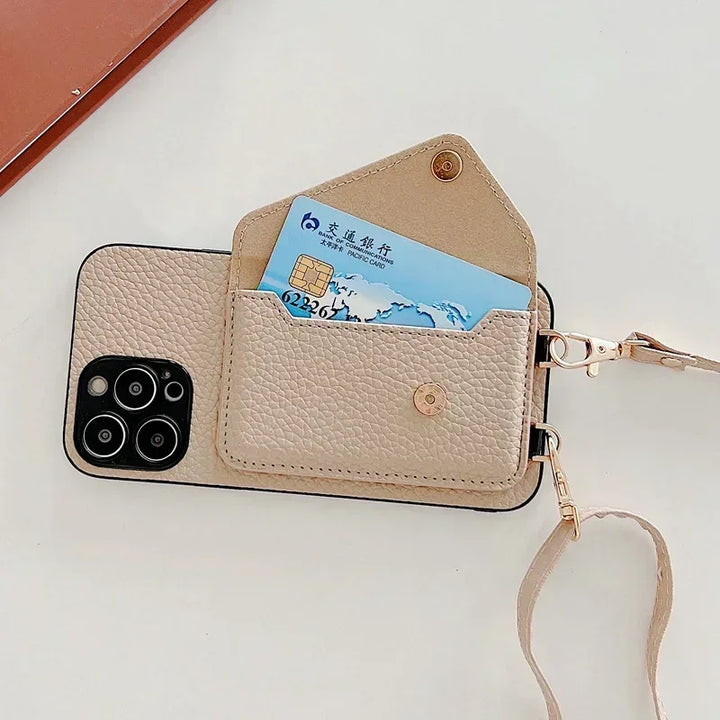 A beige phone case features a pebble-texture material with a wallet attached on the back, holding a blue bank card. The wallet has a snap button and matching beige strap with gold hardware, all laid elegantly on a white surface.