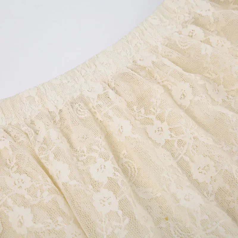 Close-up of a cream-colored silky lace fabric with a floral pattern, gathered with an elastic high waist.