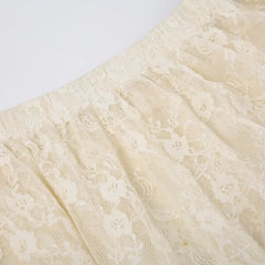 Close-up of a cream-colored silky lace fabric with a floral pattern, gathered with an elastic high waist.